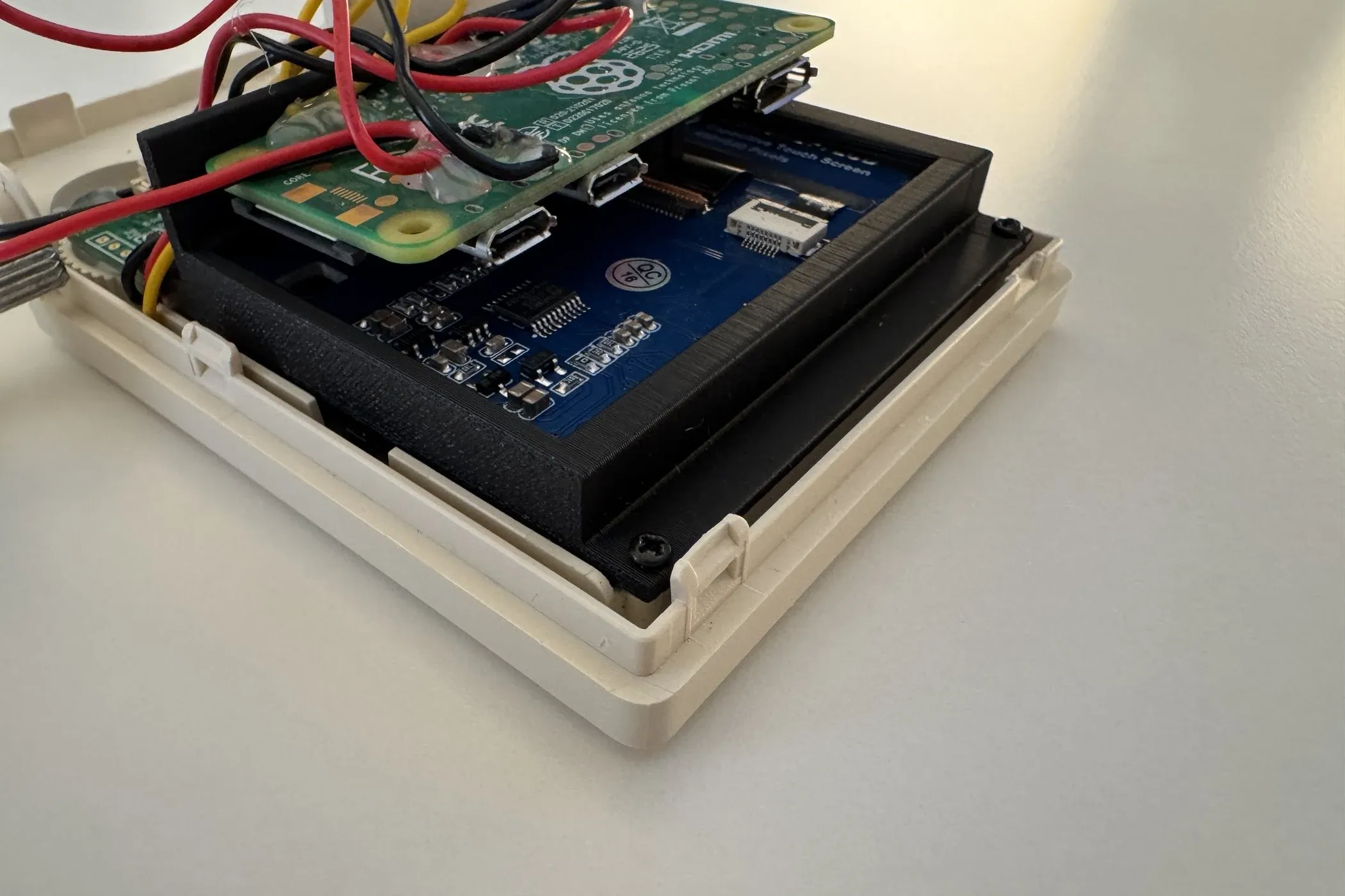 The bracket seated in the shell, holding the display with the Raspberry Pi Zero mounted on top of it