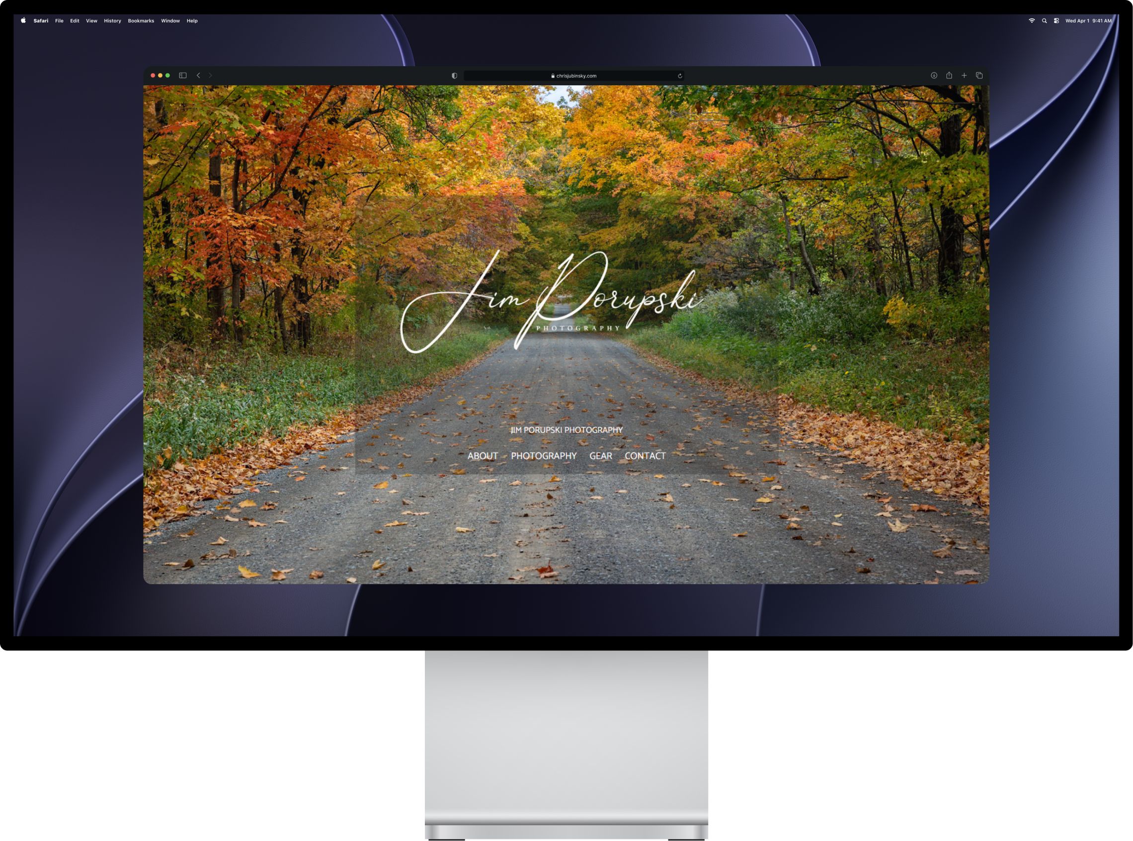 The photography site's homepage on a desktop monitor, a full-width autumn road photograph behind the studio name and nav